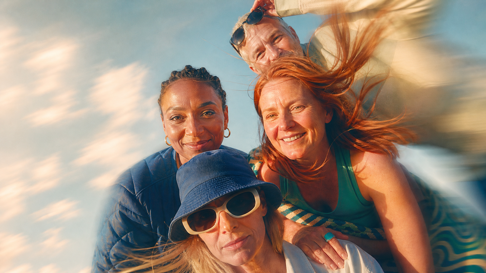 Four members outdoors in warm sunlight, smiling together.
